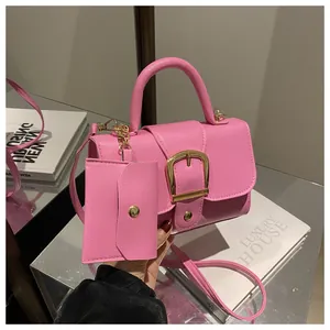 Detailed macro view of pink litchi grain leather handbag with gold metal buckle