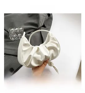 Detail showing the white pleated texture and round handle of a crescent-shaped cloud bag