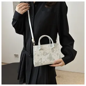 Detail of white faux leather crossbody bag with green butterfly and star print