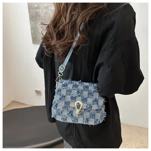 Détail du sac bandoulière en denim à carreaux bleus avec bords effilochés dorés
