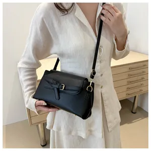 Detail showing the chic golden buckle and textured black leather flap of the square bag