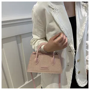 Detail of pink woven texture mini handbag with crossbody strap and fashion brand tag
