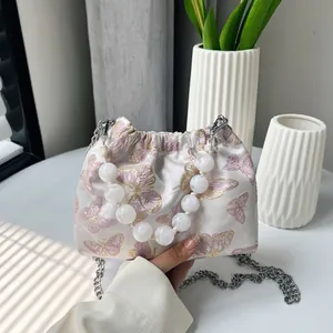 Detail der Schmetterlingsstickerei auf Seidenbeuteltasche mit Perlen- und Metallkette