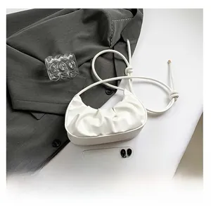 Detail view of white ruched crescent bag with golden strap hardware and phone size comparison