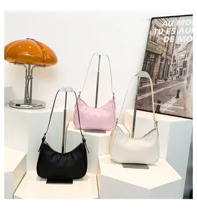 Three half-moon hobo bags in black, pink, and beige displayed on geometric stands