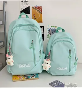 Mint green nylon backpacks in two sizes with bear charm and HOKEAM logo branding