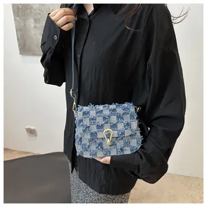 Détail du sac à bandoulière en denim à carreaux avec bords effilochés et fermoir doré