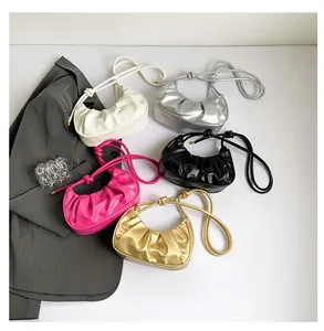 Flat lay of pleated crescent bags in white, silver, black, rose, and gold faux leather