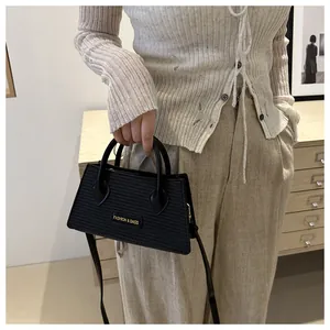 Detail of black woven texture handbag with golden logo plate and sturdy top handles