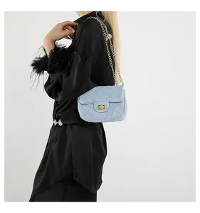Detail of light blue quilted denim bag with gold chain strap and turn-lock closure