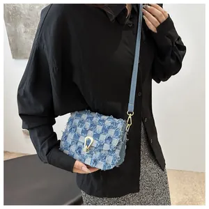 Détail du sac bandoulière en denim damier avec bords effilochés et boucle dorée chic