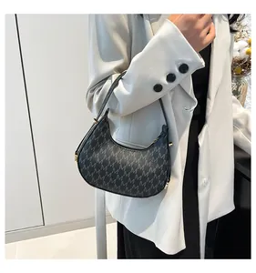 Model wearing a vintage black hobo bag with grey M pattern and gold hardware details
