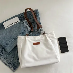 Minimalist white tote bag with leather straps and chain detail for daily commuting