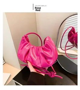 Detail view of the rose red pleated dumpling bag with decorative knot shoulder strap