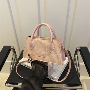 Straw and leather tote bag with gold logo on a 45-degree angle held by model
