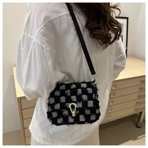 Détail du sac à bandoulière en denim à carreaux avec bords effilochés et fermoir doré