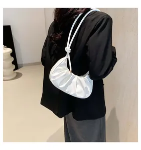 Detail of white pleated crescent bag with knot shoulder straps on female model