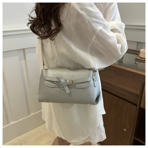 Detail of silver metallic crossbody bag with knot decor and golden hardware on a white shirt