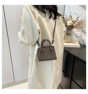Close-up of brown small square bag with M-pattern print and detachable shoulder strap