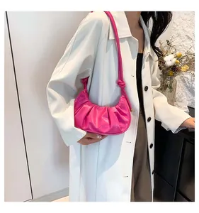 Detail of rose pink pleated dumpling bag with knot shoulder strap on white coat