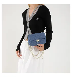 Detail of blue denim crossbody bag with gold chain strap and quilted rhombus pattern