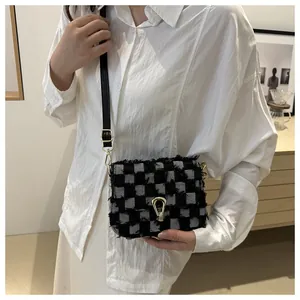 Détail du sac bandoulière en denim à carreaux avec franges et fermoir doré sur mannequin