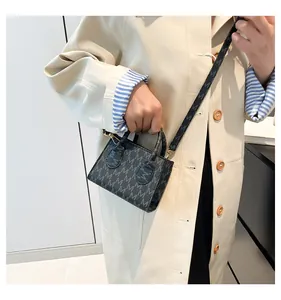 Close-up of black crossbody bag featuring gold hardware and monogram M pattern