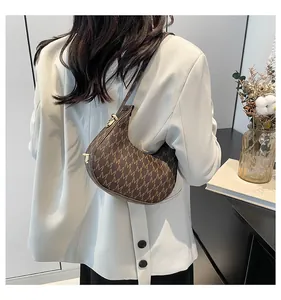 Brown vintage baguette bag with 'M' letter print shown on a shoulder in a back view