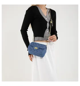 Detailed shot of blue denim crossbody bag with quilted pattern and gold chain strap