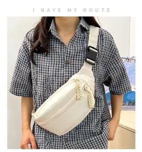Close-up of cream canvas crossbody bag featuring dual zippers and durable plastic buckle