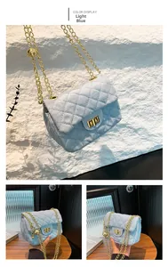 Detail view of light blue quilted shoulder bag with gold chain and ball charm