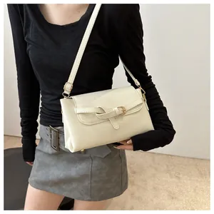 Close-up of cream square crossbody bag with decorative buckle and fine shoulder strap