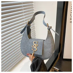 Dettaglio borsa a mezzaluna azzurra con logo SS dorato e ciondolo con nappa