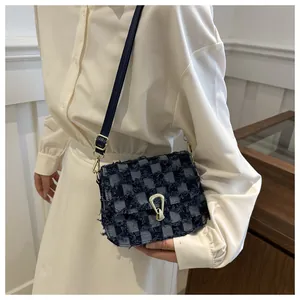 Détail du sac bandoulière en denim à carreaux avec bords effilochés et boucles dorées