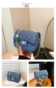 Detail of dark blue denim crossbody bag with diamond quilting and gold chain strap