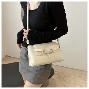 On-body shot of cream PU leather crossbody bag with decorative strap and gold buckle