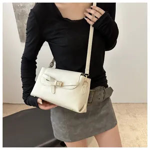 Detail view of cream white flap bag with golden bow clasp and textured leather