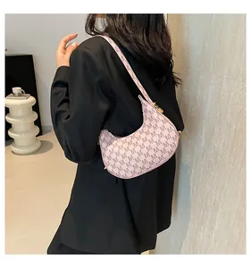 Detail of pink crescent bag with M-letter print worn by a model in a black blazer