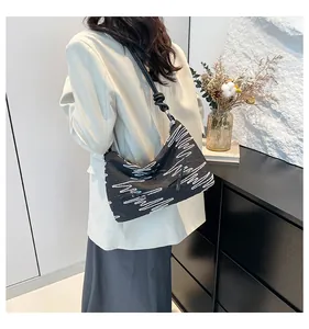 Détail du sac bandoulière noir avec broderie vagues blanches et bandoulière nouée