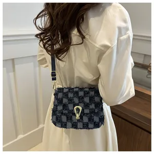 Détail du sac bandoulière en denim à carreaux avec bords effilochés et boucle en fer à cheval