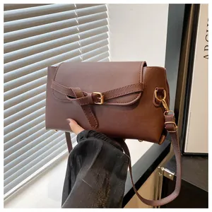 Detail of dark brown leather texture with gold buckle and adjustable strap on a flap bag