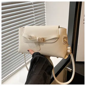 Close-up of minimalist off-white PU leather shoulder bag with golden buckle and strap