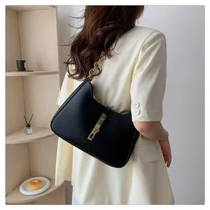 Elegante schwarze Hobo-Tasche aus Leder mit goldener Kette, getragen von einem Model