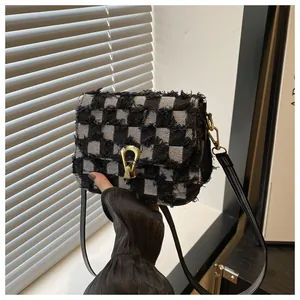 Gros plan du tissu denim à carreaux noir et blanc avec boucle dorée en fer à cheval