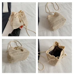 Detalle del bolso de paja tejida beige con cierre de cordón y borlas de cuentas metálicas