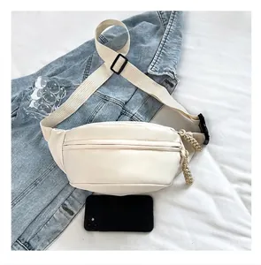 White minimalist sling bag shown on denim jacket for size comparison with a phone