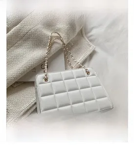 Dettaglio macro della borsa trapuntata bianca con catena dorata e texture morbide