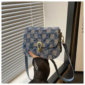 Détail du sac bandoulière en denim à carreaux avec bords effilochés et boucle dorée