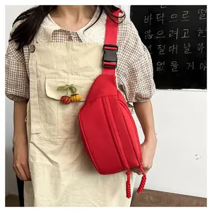 Detail of red nylon crossbody bag featuring adjustable strap and secure plastic buckle