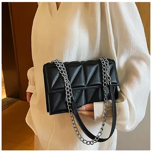 Détail du sac bandoulière matelassé noir avec coutures géométriques et chaîne argentée